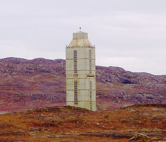 Rusty abandoned tower standing alone on barren land with hills in the background, one of the scariest places around the world.