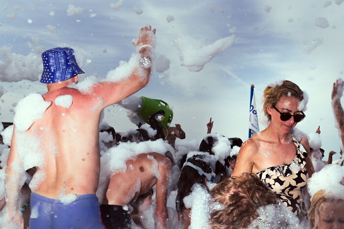 Crowd covered in foam at an outdoor event capturing a lively moment in perfectly-timed street photos by Luca Regoli