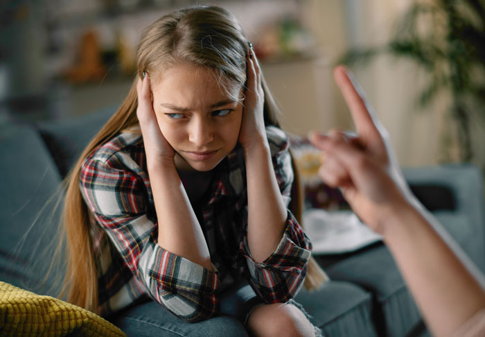 Young woman in a therapy session covering her ears, experiencing intense emotions during insane revelations in therapy.