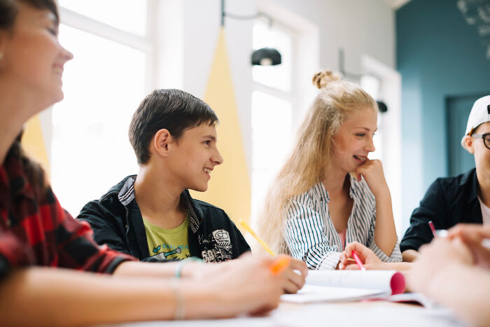 Teenagers smiling and working together in a bright classroom, illustrating out-of-touch rich people flaunted wealth moments.