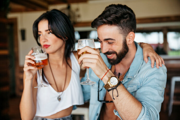 Couple on a date in a bar raising drinks, capturing a moment from sour dates where a safe word was needed.