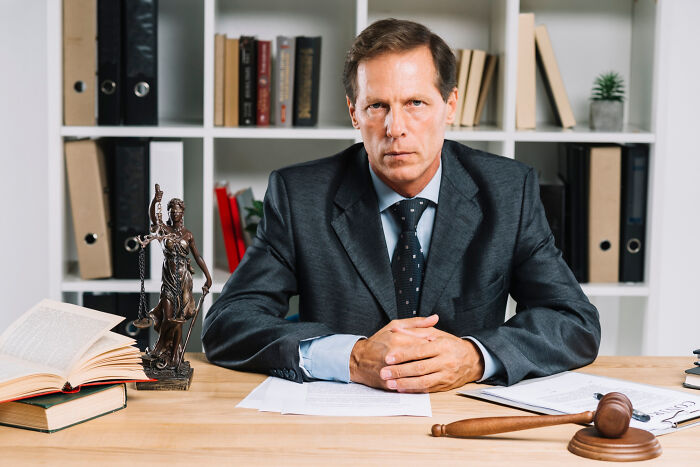 Man in a suit at a desk with legal books and a gavel, representing professions attracting the most awful people. - 14