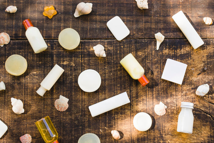 Travel hacks essentials including small bottles and containers for toiletries arranged on a wooden surface with seashells.