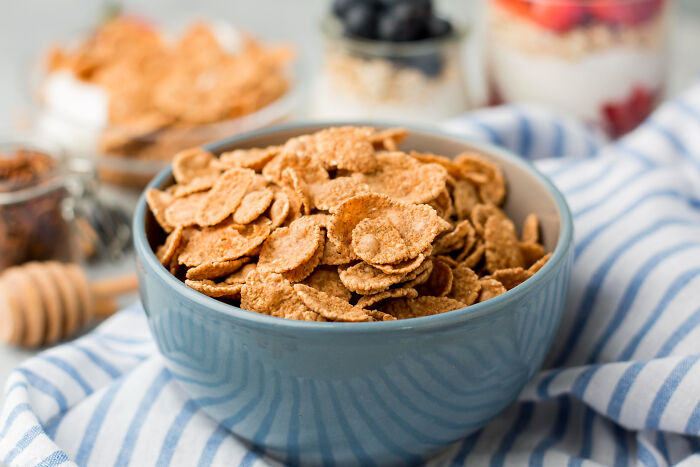 Bowl of healthy breakfast cereal flakes representing the best processed foods for weight loss on a striped cloth.