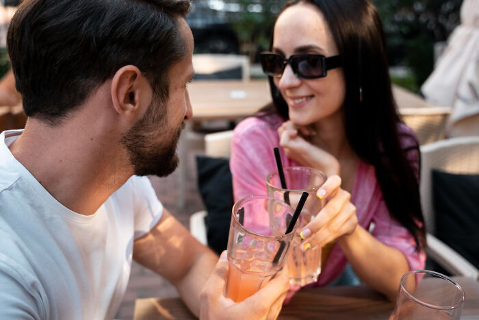 Couple on a date at a bar clinking glasses, highlighting dates that went sour and use of a safe word.