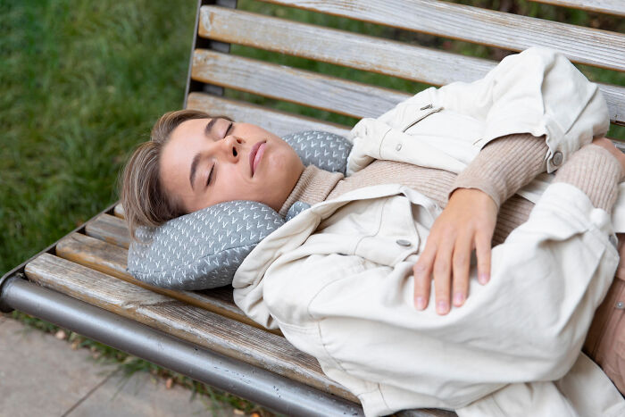 Young woman resting on a park bench using a travel neck pillow, illustrating European netizens correcting common country misconception facts.