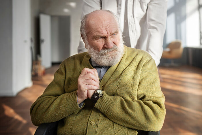Elderly man in a green cardigan looking concerned while sitting, illustrating deepest secrets parents kept from kids