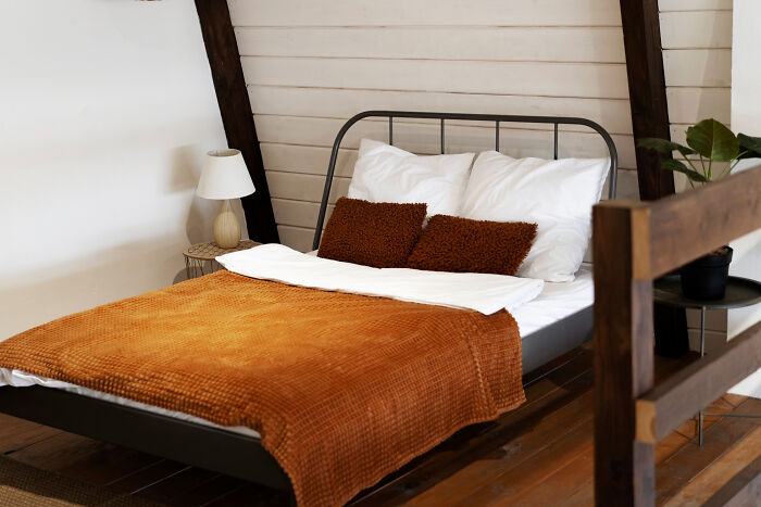 Cozy bedroom with a metal bed frame, white pillows, and a rust-colored blanket highlighting completely legal total psychopath style.