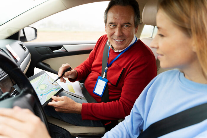 Driving instructor explaining road map to young woman in car, illustrating professions that attract the most awful people. - 26