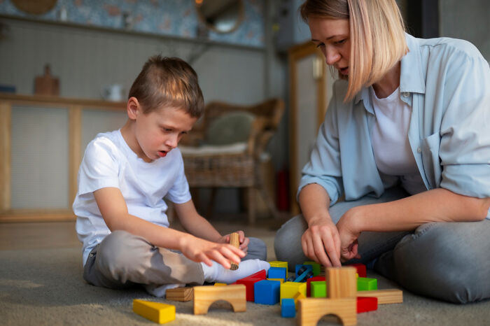Mother and son building with colorful wooden blocks indoors, illustrating deep secrets parents kept from their kids.