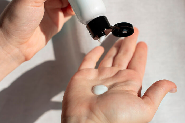 Hand squeezing lotion from a bottle onto palm, illustrating poor people habits related to skincare routines.