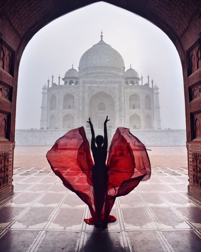 Silhouette of a person posing with flowing red fabric in front of the Taj Mahal in a breathtaking travel photo.