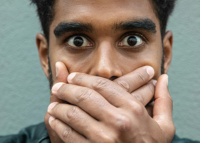 Close-up of a nervous man covering his mouth, expressing emotions often shared by dads inside the birthing room for the first time.