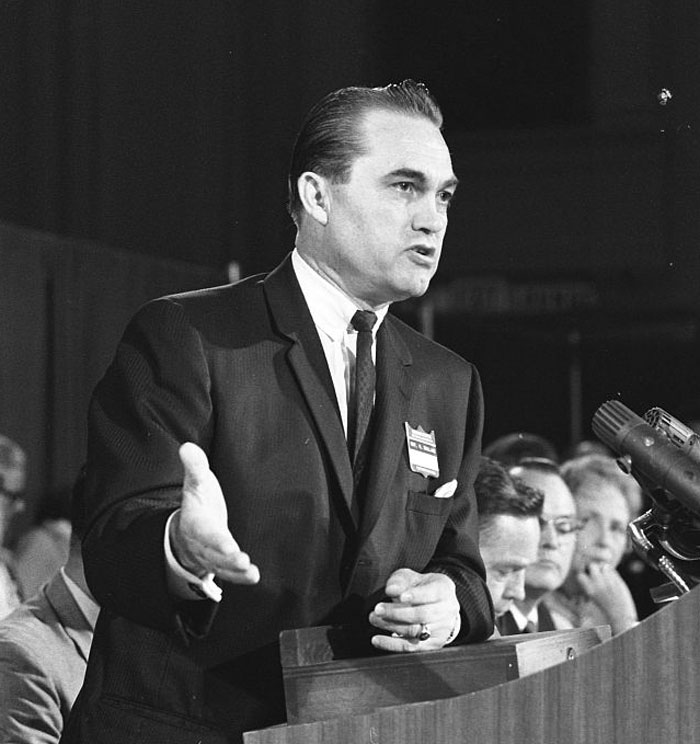 Man in a suit speaking at a podium with microphone, representing famous people who did evil things in the past ignored.