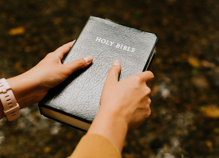 Person holding a Holy Bible outdoors, reflecting on faith and choices as one of the biggest mistakes of their lives.