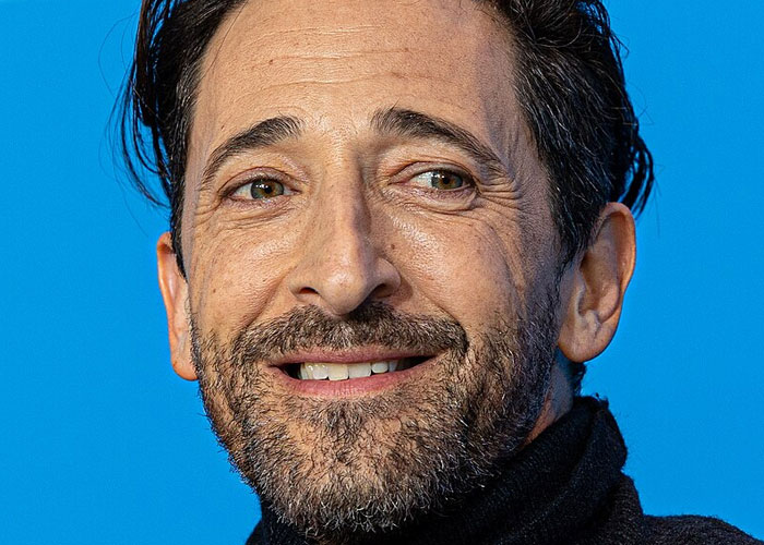 Close-up of a smiling man with dark hair and beard, representing celebrities before fame found them in a candid moment.