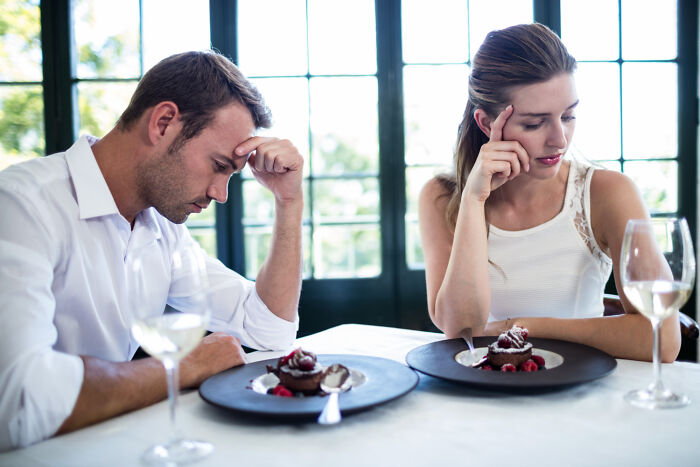 Man and woman appearing frustrated during a modern dating dinner, highlighting challenges of modern dating experiences.