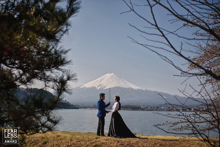 Couple holding hands by a lake with snowy mountain backdrop in an unforgettable wedding photo.
