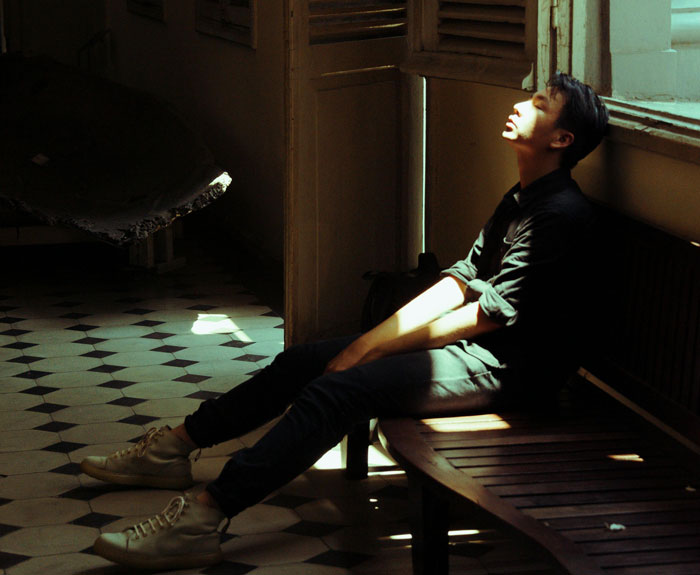 Young man sitting in sunlight by a window, reflecting on challenges of how I paid for college secrets.