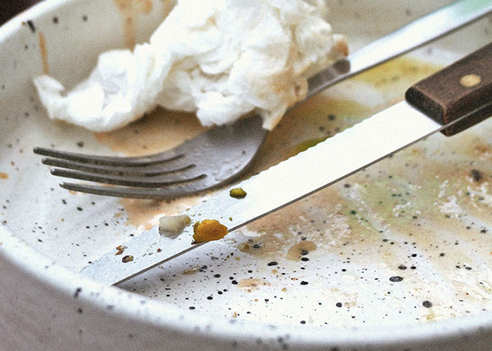 Dirty plate with leftover food, fork, and knife, illustrating messy situations buffet workers often encounter.