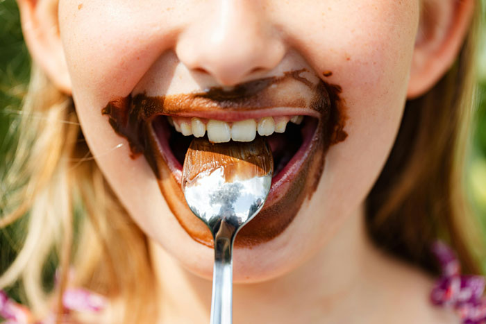 Close-up of a millennial child enjoying chocolate pudding, highlighting Millennials biggest lies shared growing up concept.