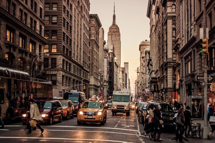 Busy city street with taxis and pedestrians, featuring a view of a tall skyscraper in breathtaking travel photos.