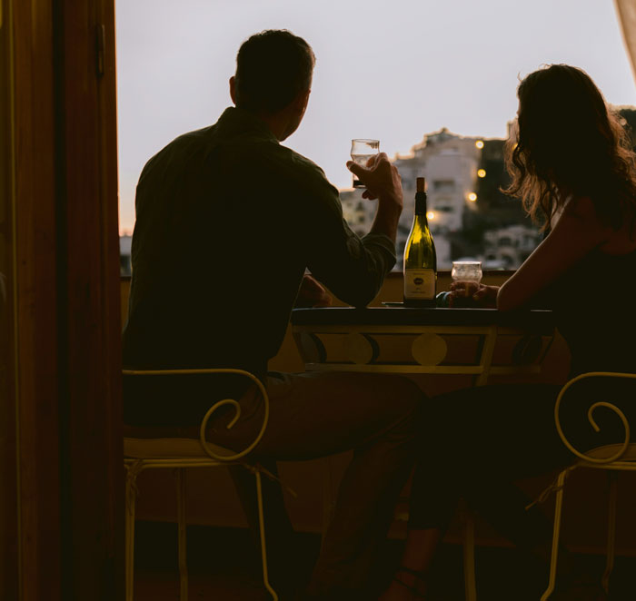 Couple sitting at a table with drinks during sunset, representing toxic dating trends people weirdly accept as normal.