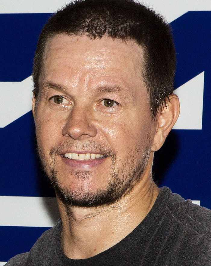 Close-up of a man with short hair and facial stubble smiling, representing famous people known for evil actions ignored by the world.