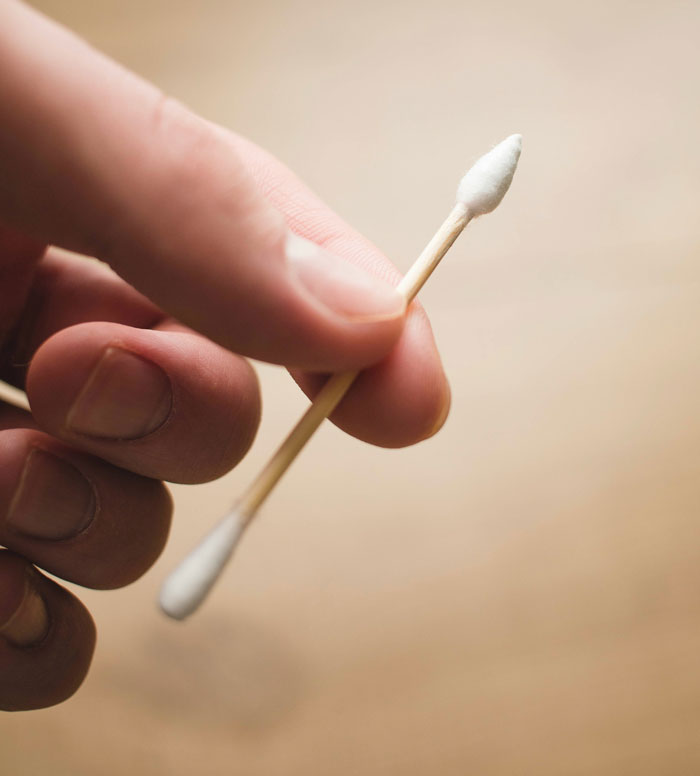 Hand holding a cotton swab with a blurred background, related to how I paid for college secrets.