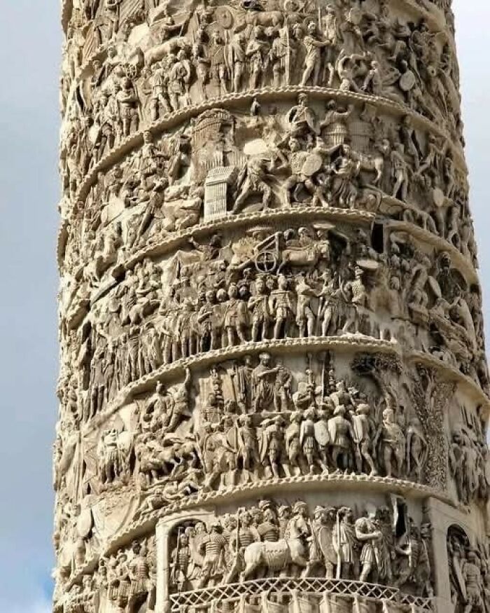 Detailed ancient stone carvings on a historic column showcasing scenes from archaeology world and historical events.