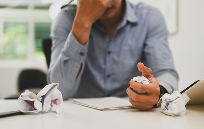 Man in a blue shirt holding crumpled paper, appearing stressed during a therapy session with intense emotional revelations.
