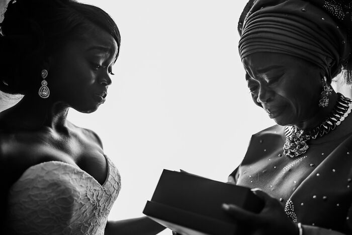 Bride and older woman sharing an emotional moment while looking at a gift in unforgettable wedding photos.