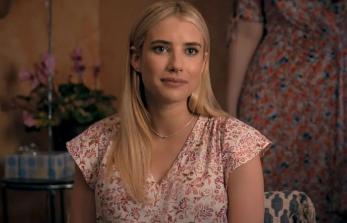 Young woman with blonde hair wearing a floral dress sitting indoors, representing famous people who did evil things.