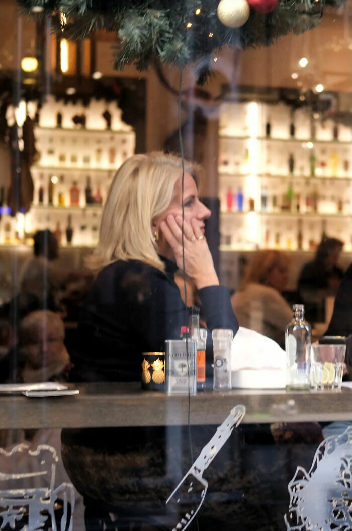 Blonde woman sitting in a cafe, captured in a beautiful street shot reflecting the poetry of everyday life.