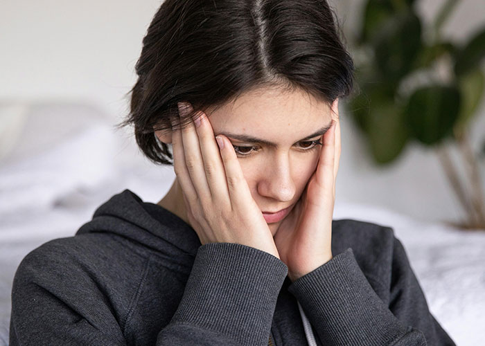Young woman looking distressed and thoughtful, reflecting on reasons for called off engagements and heartbreak.
