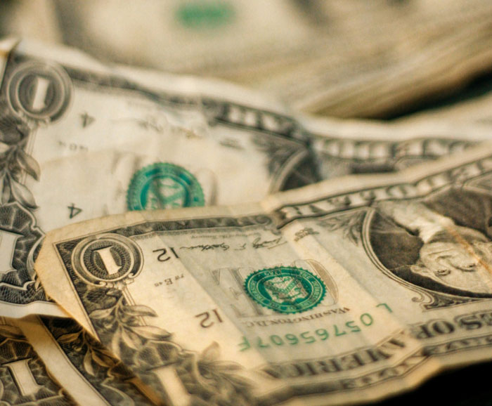 Close-up of worn US dollar bills representing financial mistakes as a common biggest mistake described by people.