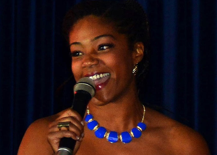 Female celebrity smiling and speaking into microphone, showcasing what celebrities were doing before fame found them.