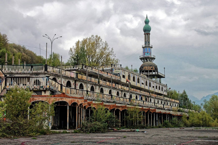 Abandoned eerie building with graffiti and overgrown vegetation, one of the scariest places around the world for brave travelers.