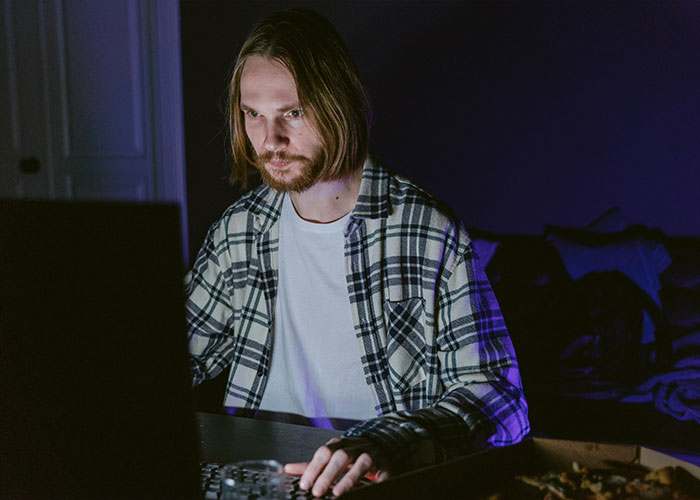 Man focused on laptop screen in dark room, illustrating a take one for the team moment during late work hours.