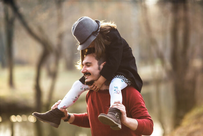 Man carrying child on shoulders in autumn forest, illustrating close family bonds and secrets parents kept from kids.