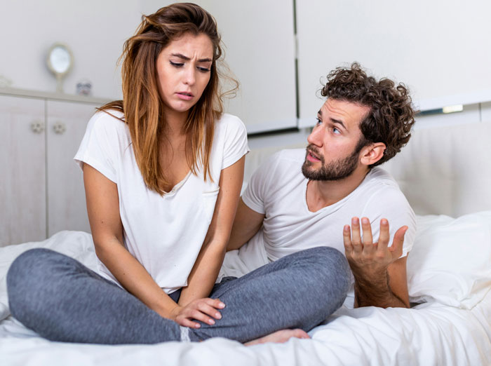 A couple sitting on bed showing signs of distress, illustrating toxic dating trends in modern relationships.