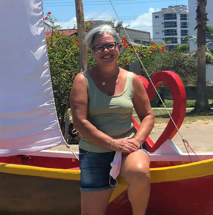 Woman sitting outdoors near a heart decoration, related to teen losing her life after eating cake with note from secret admirer.
