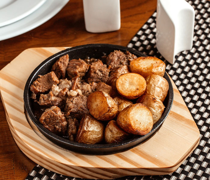 Plate of cooked meat and roasted potatoes served in a skillet, illustrating people committed to a lie way too hard.