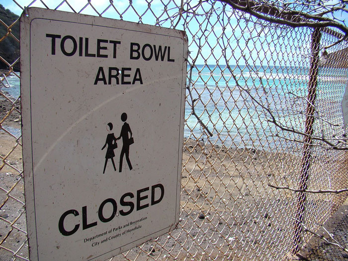 Warning sign on a rusted fence near a remote coastal area, part of some of the scariest places around the world.