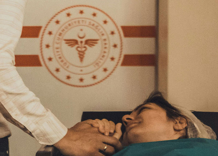 Father holding his partner’s hand, experiencing emotions inside the birthing room for the first time during childbirth.