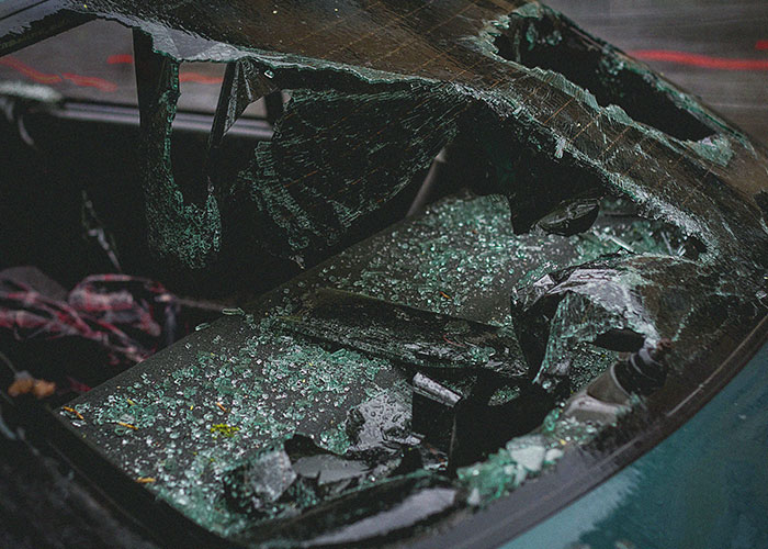 Shattered car windshield with broken glass and metal fragments after a severe accident or impact, illustrating take one for the team moment.