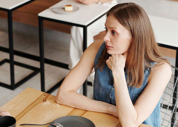 Young woman looking awkward and uncomfortable during a tense and painful date at a restaurant table.