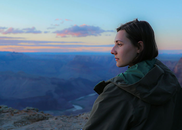 Young woman sitting alone at sunset, reflecting on relationships and reasons people called off their engagements.