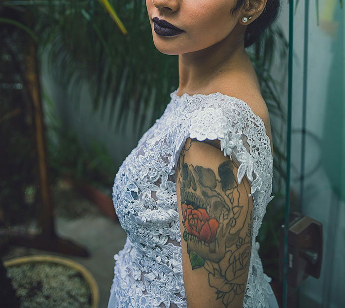 Woman in lace dress showing tattooed arm, symbolizing personal stories on how paid for college secrets revealed.