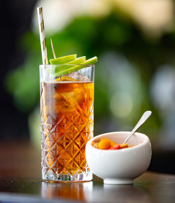 Glass of iced herbal tea with fresh apple slices and a bowl of natural remedy, illustrating effective old wives' tales.